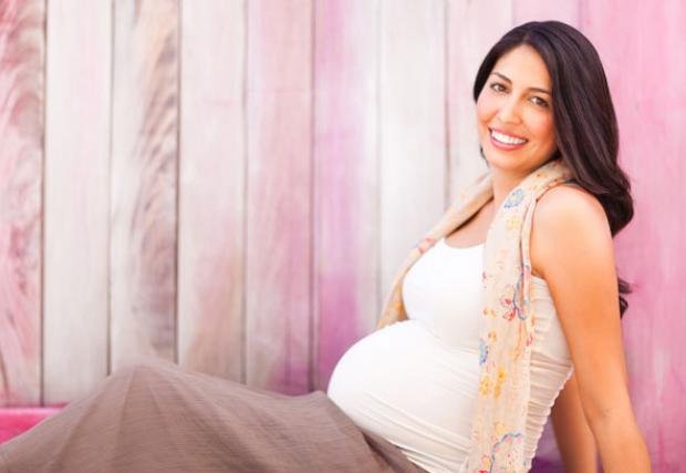 Pregnant woman sitting on the ground smiling