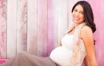 Pregnant woman sitting on the ground smiling